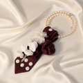 Deep burgundy satin necktie necklace with handcrafted fabric rose and pearl daisy accents displayed as flat lay on ivory silk