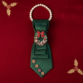 Emerald green brocade necktie necklace with rhinestone Christmas wreath brooch displayed as flat lay on red velvet with gold holly accents